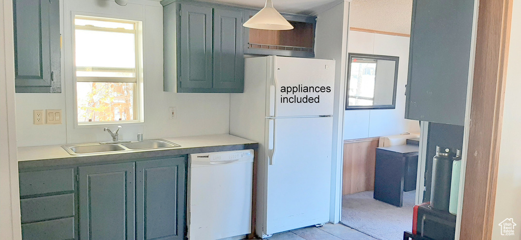 Kitchen featuring light carpet, white appliances, hanging light fixtures, and sink