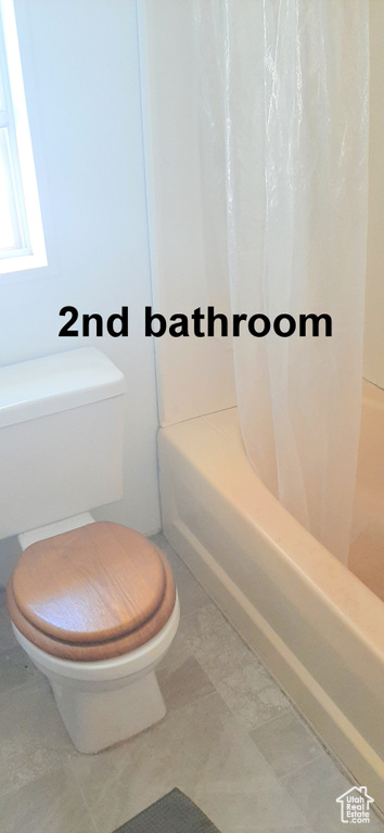 Bathroom featuring tile patterned flooring, toilet, and shower / tub combo with curtain