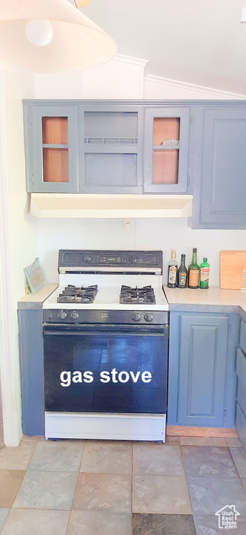 Kitchen featuring blue cabinetry, white gas range oven, and vaulted ceiling