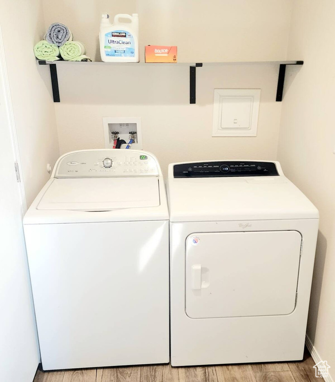 Clothes washing area featuring light hardwood / wood-style floors and washing machine and clothes dryer