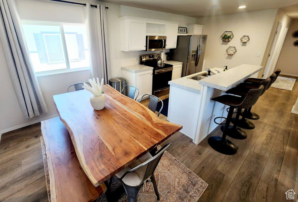 Dining space with sink and dark wood-type flooring