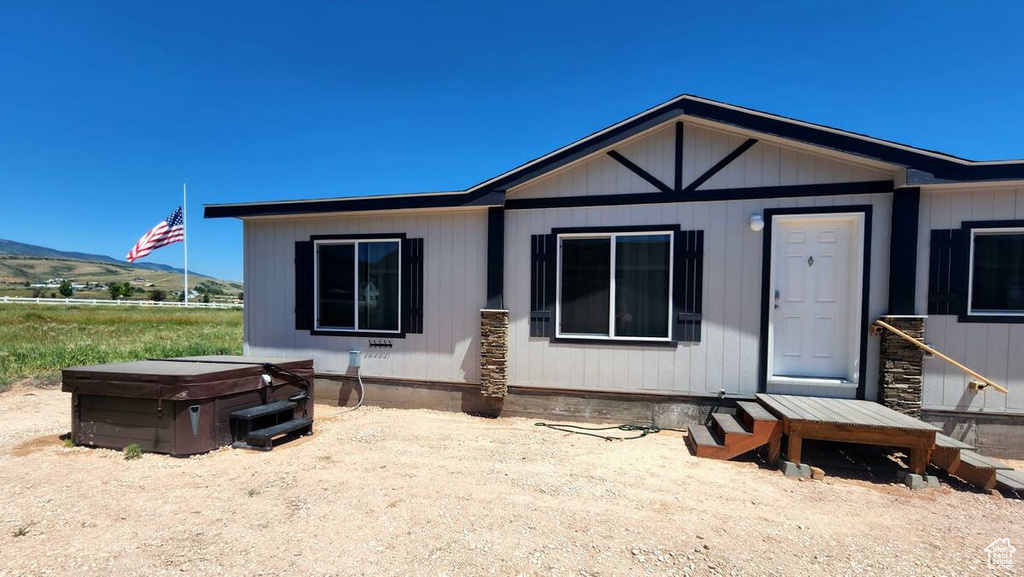View of front of property with a mountain view and a hot tub