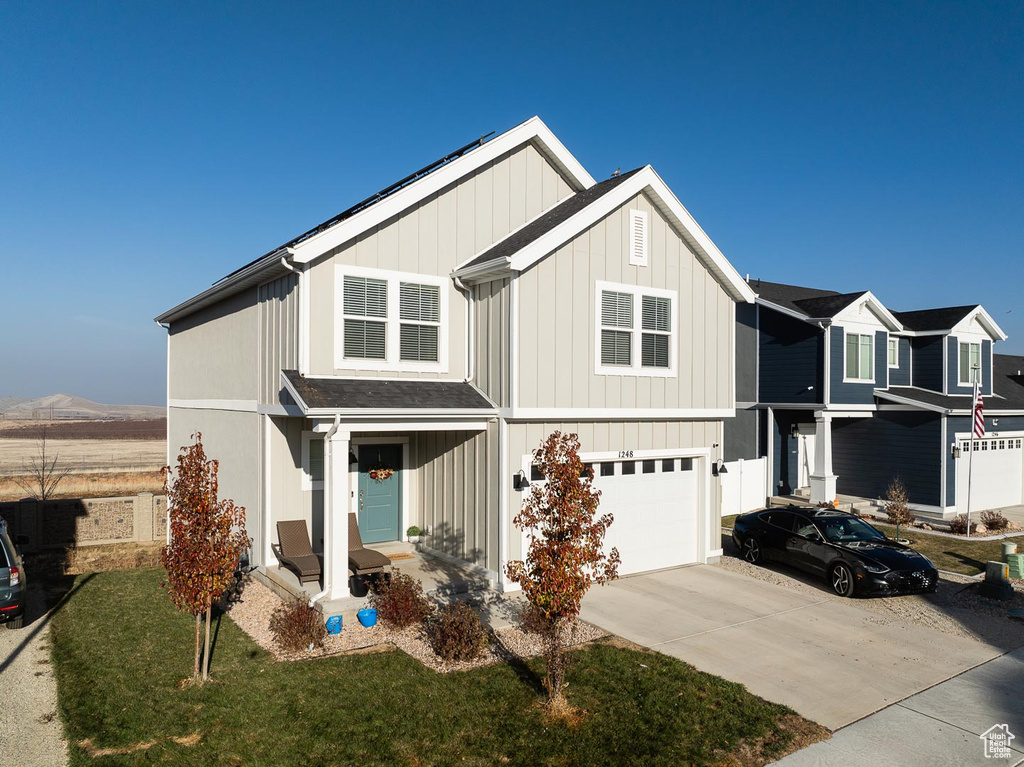 View of front of house with a mountain view, a front lawn, and a garage