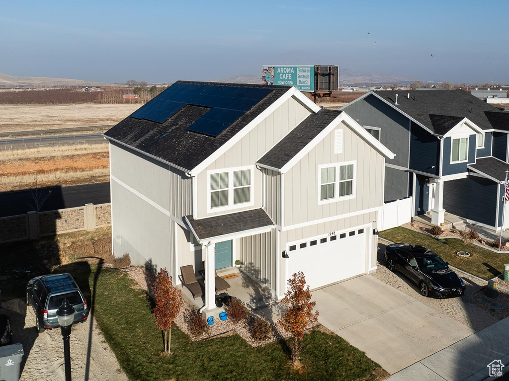 View of front of home featuring solar panels and a garage