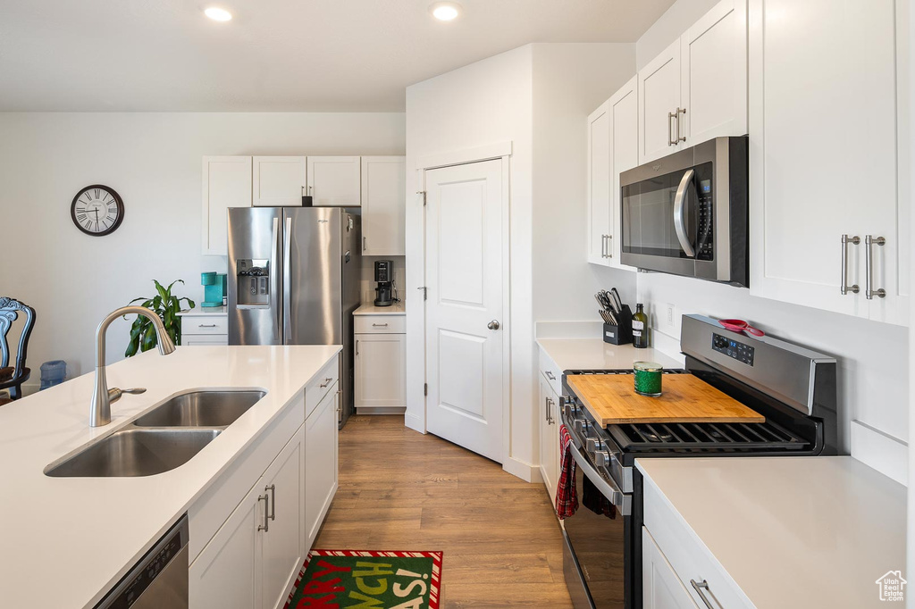 Kitchen featuring appliances with stainless steel finishes, light hardwood / wood-style flooring, white cabinetry, and sink