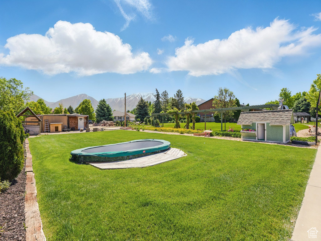 View of green lawn featuring a mountain view and an outdoor structure