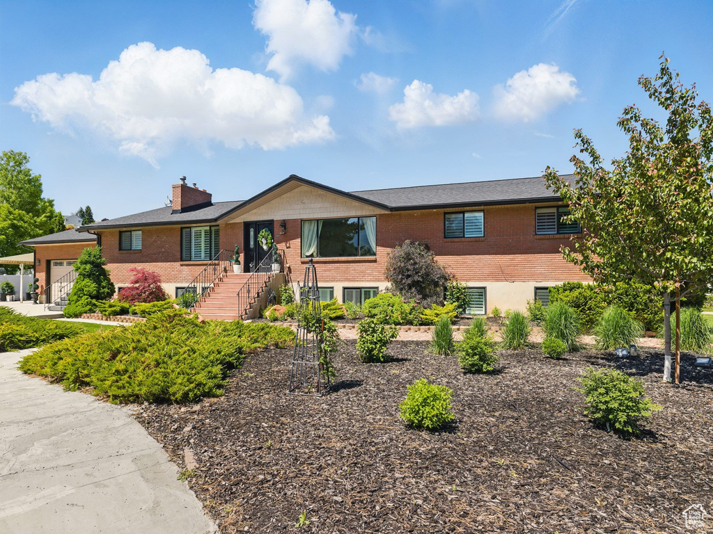 Ranch-style home featuring brick siding, an attached garage, and a chimney