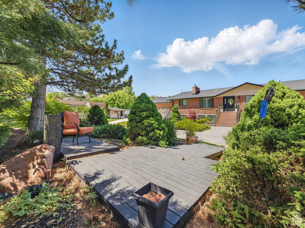 Back of house featuring a wooden deck, a chimney, and brick siding