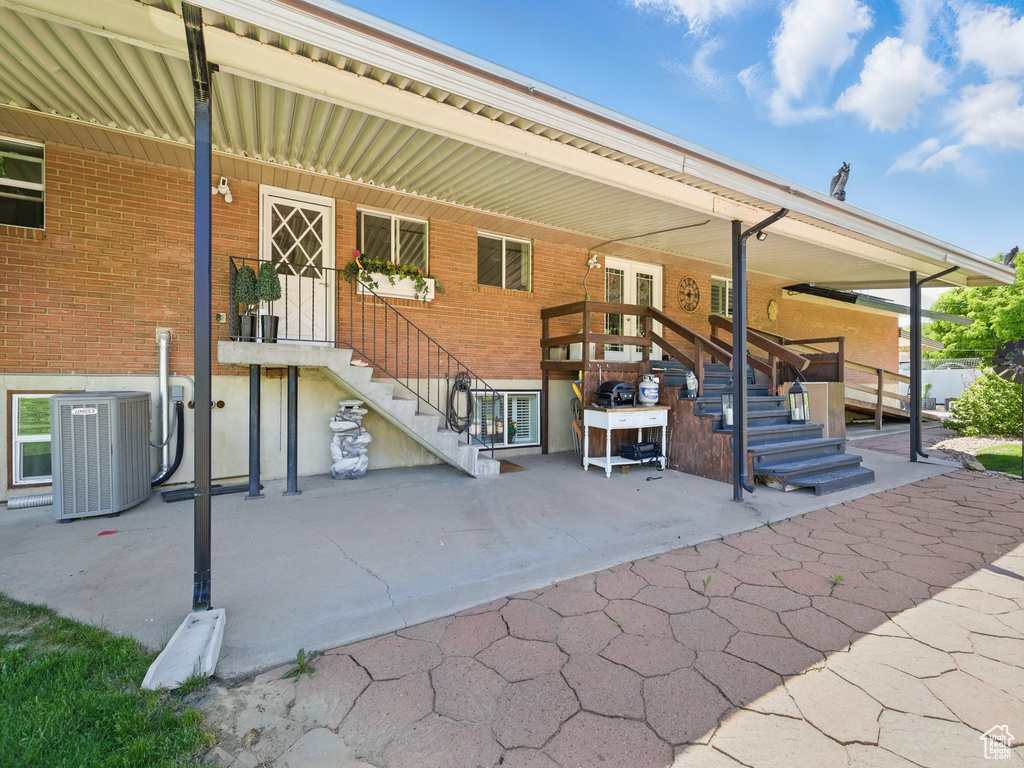 Rear view of house with central AC, stairway, and brick siding