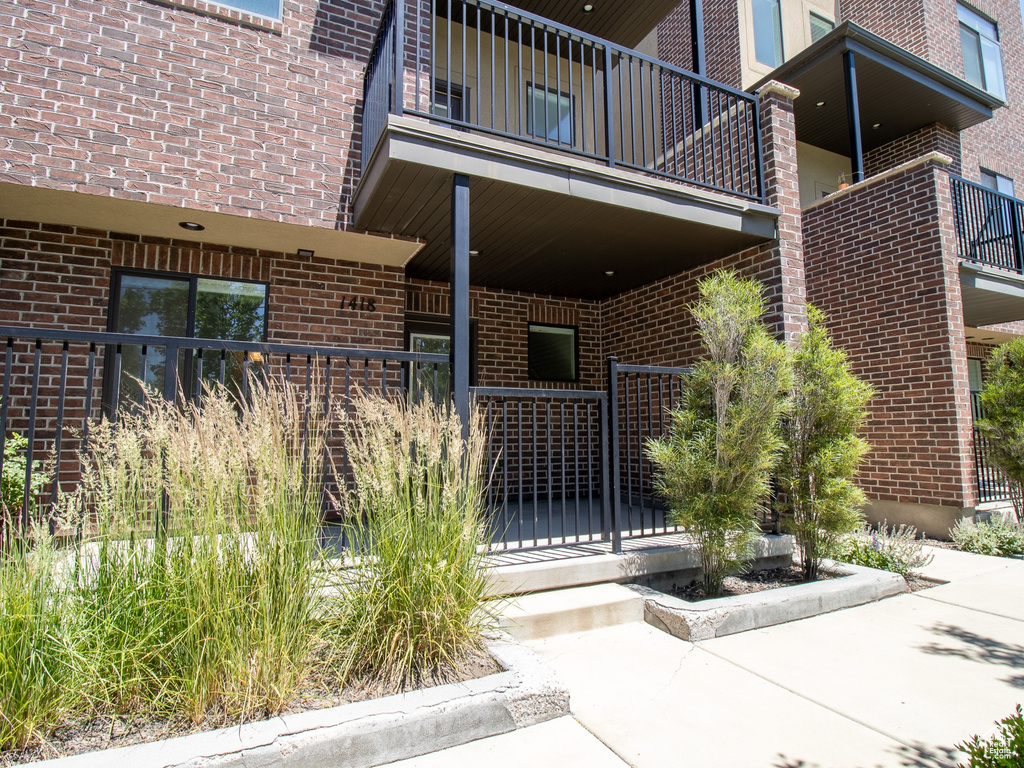 Entrance to property featuring a balcony and brick siding
