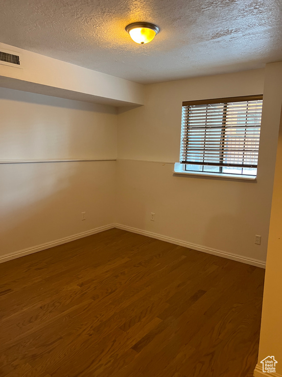 Spare room with a textured ceiling and dark hardwood / wood-style flooring