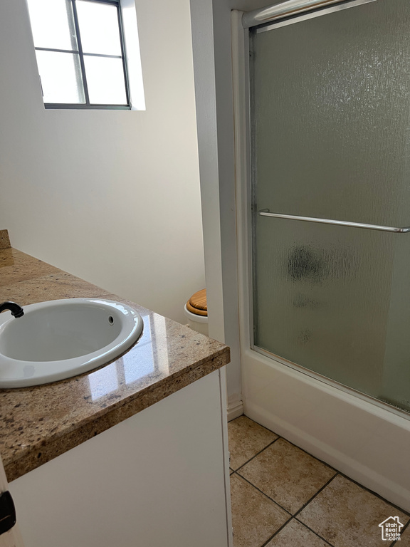 Full bathroom with shower / bath combination with glass door, vanity, tile patterned floors, and toilet