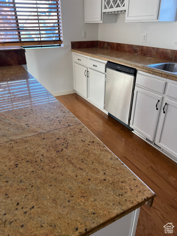 Kitchen with dishwasher, wood-type flooring, and white cabinets