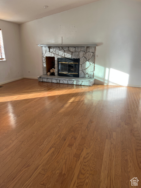 Unfurnished living room with hardwood / wood-style floors and a stone fireplace