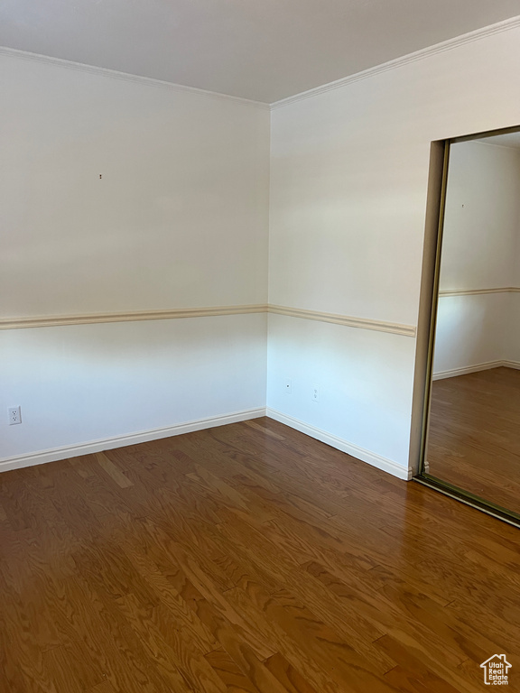 Empty room with wood-type flooring and crown molding