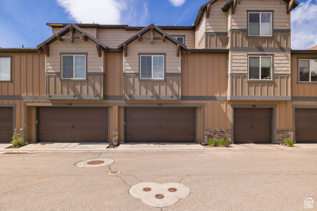 Multi unit property featuring board and batten siding, stone siding, and a garage