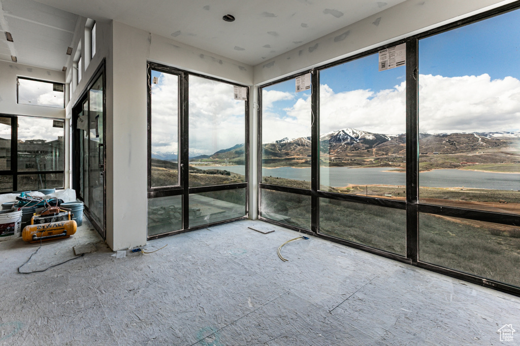 Unfurnished sunroom featuring a water and mountain view