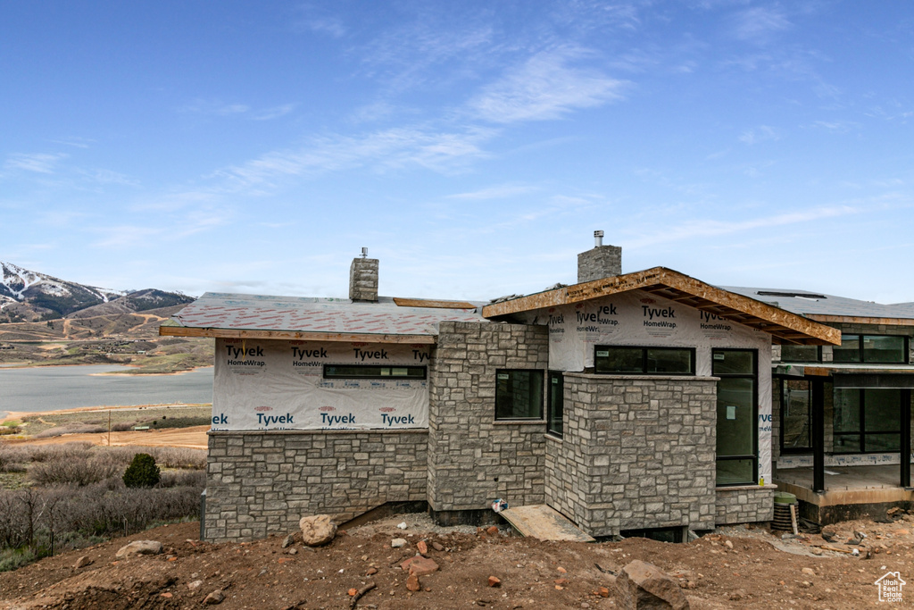 Back of house featuring a chimney and stone siding