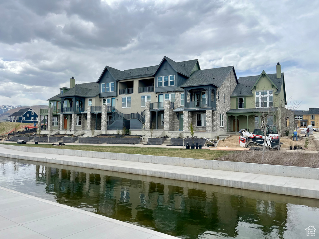 Back of property with a water view, a chimney, a residential view, and a balcony