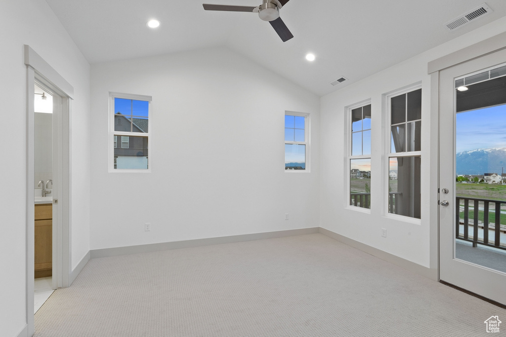 Unfurnished room featuring lofted ceiling, healthy amount of natural light, a ceiling fan, light colored carpet, and recessed lighting