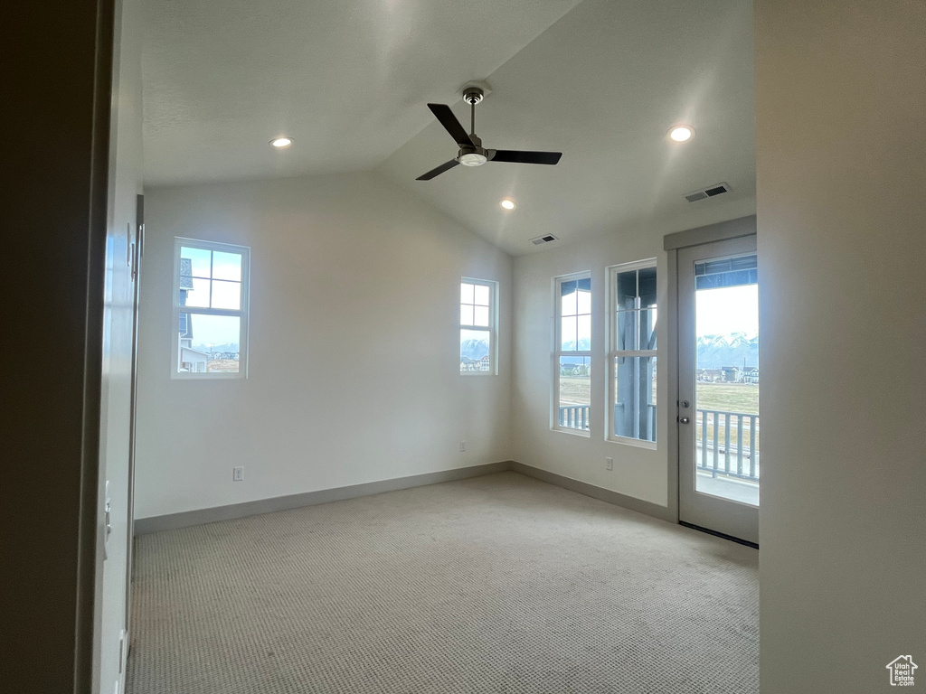 Carpeted empty room featuring visible vents, ceiling fan, baseboards, and vaulted ceiling