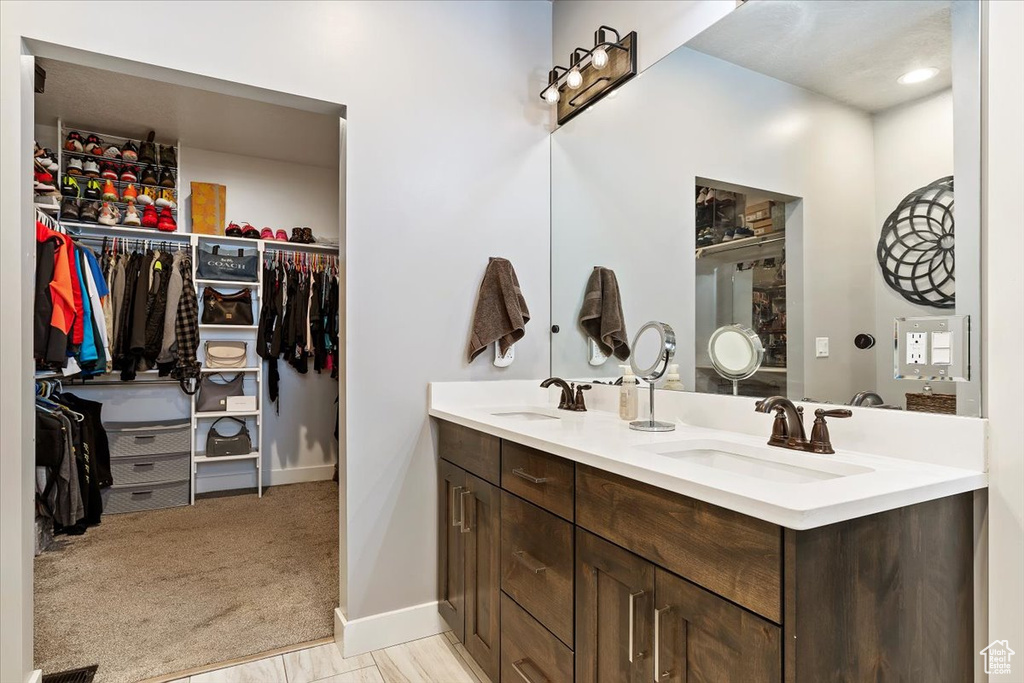 Bathroom with double vanity, baseboards, and a spacious closet