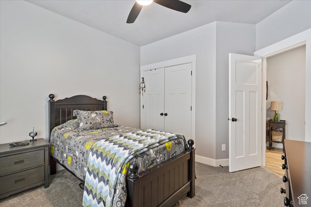 Carpeted bedroom with a closet, baseboards, and a ceiling fan