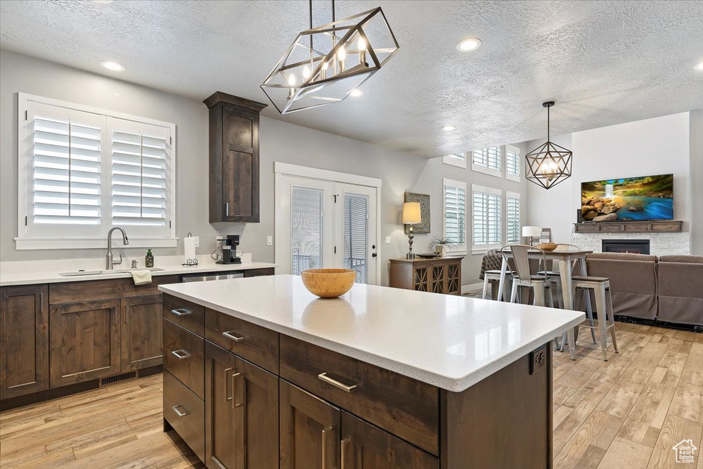 Kitchen featuring a textured ceiling, a sink, light wood-style flooring, light countertops, and open floor plan