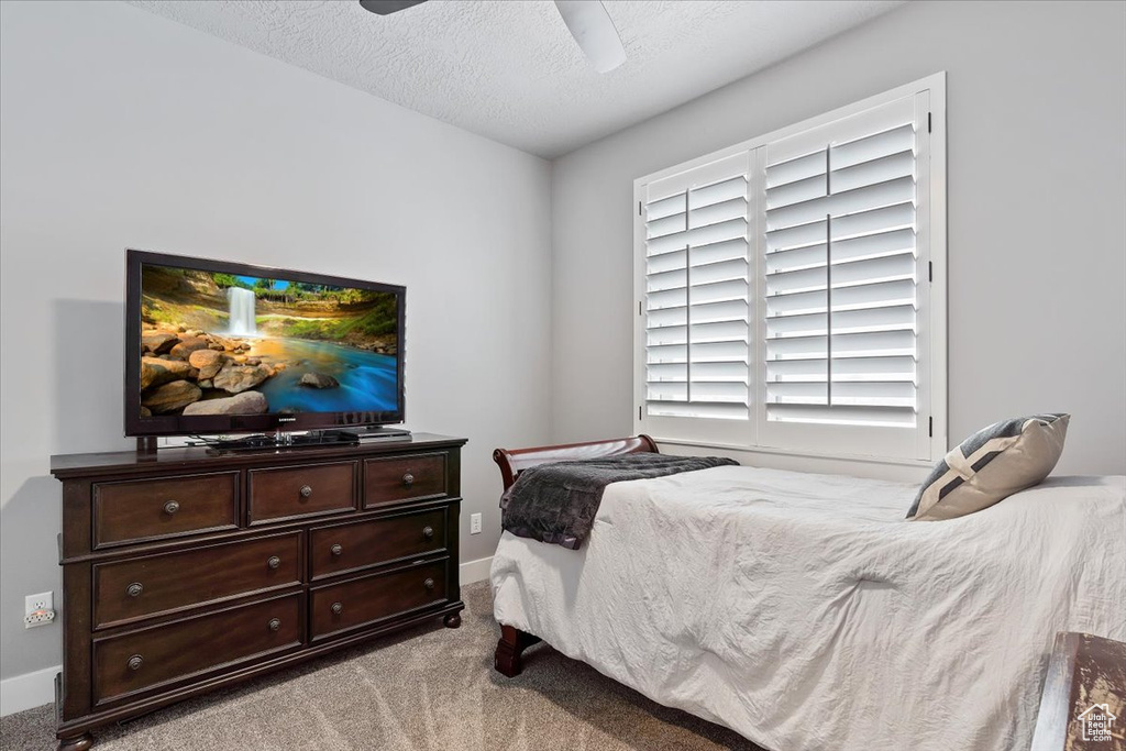 Bedroom featuring carpet, baseboards, a textured ceiling, and a ceiling fan