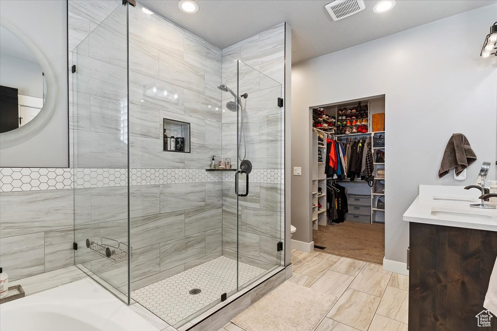 Bathroom featuring a shower stall, vanity, a spacious closet, recessed lighting, and baseboards