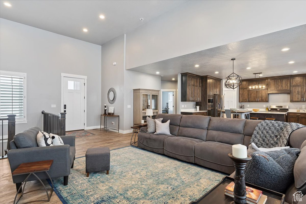 Living room featuring recessed lighting, a high ceiling, baseboards, and light wood-type flooring