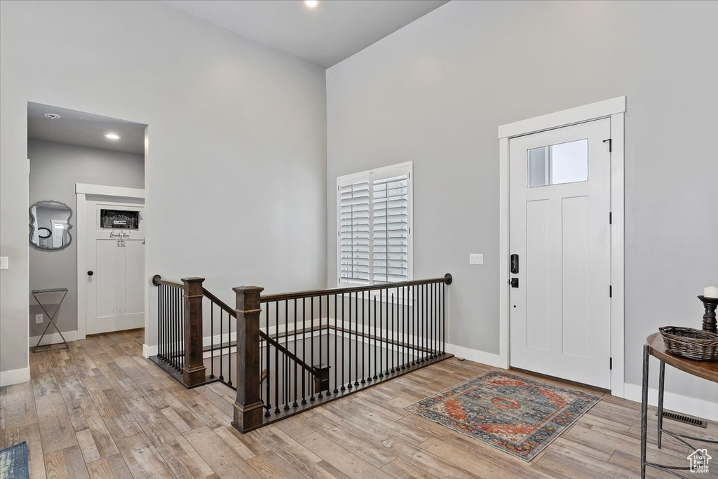 Foyer featuring wood finished floors, baseboards, a towering ceiling, and recessed lighting