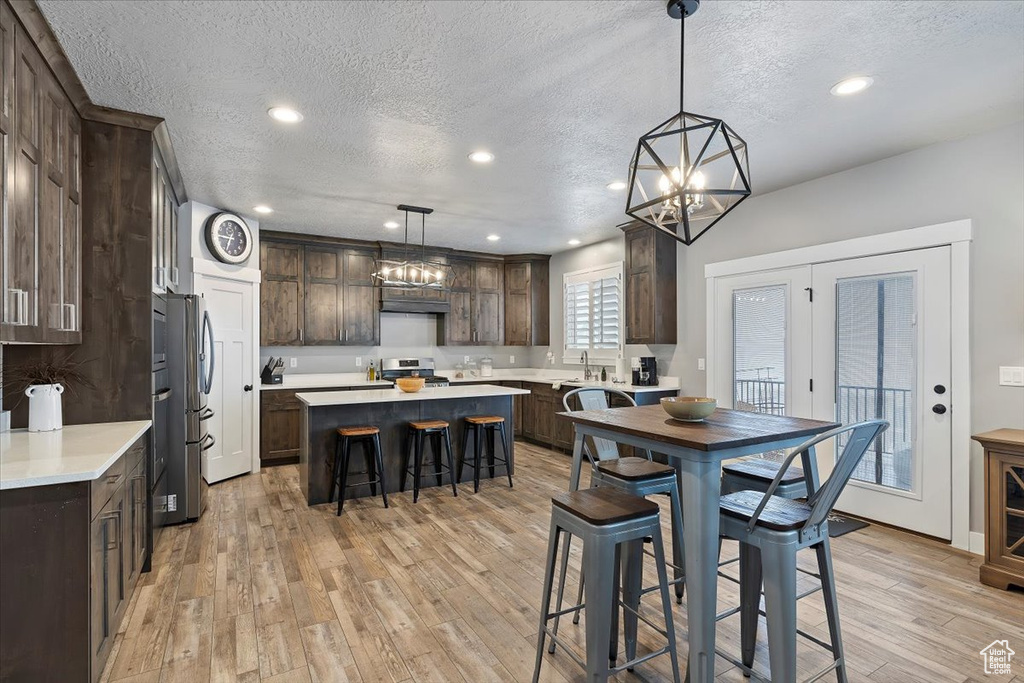 Dining space with a textured ceiling, light wood finished floors, a chandelier, and recessed lighting
