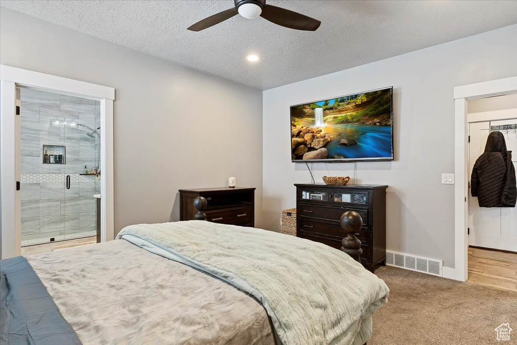 Bedroom with baseboards, carpet, ensuite bath, a textured ceiling, and ceiling fan