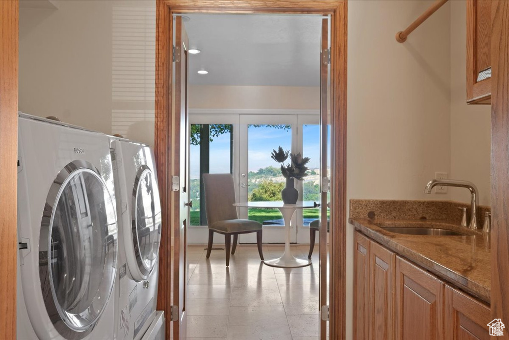 Clothes washing area featuring cabinets, french doors, and sink