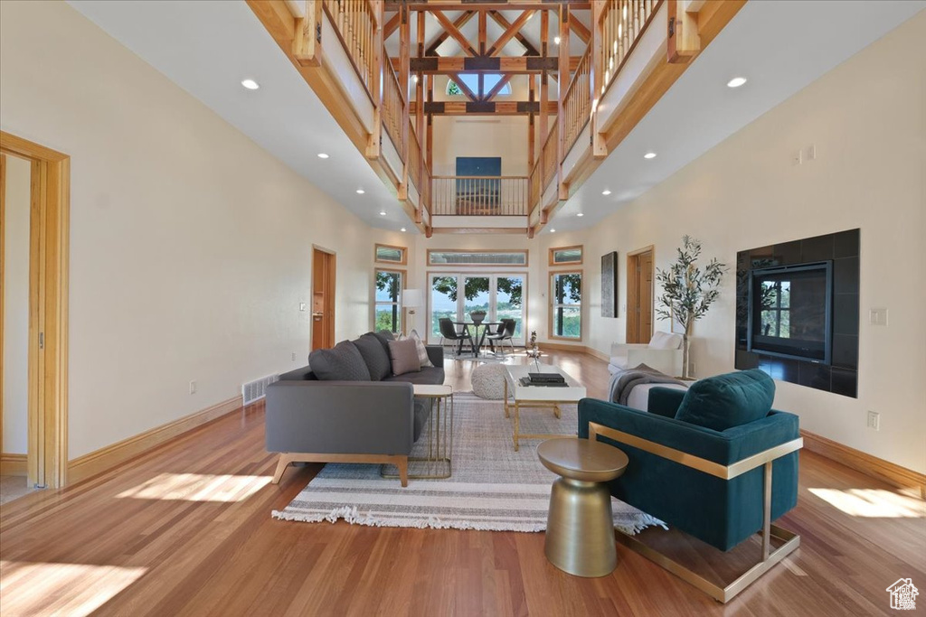 Living room with french doors, a towering ceiling, and light wood-type flooring