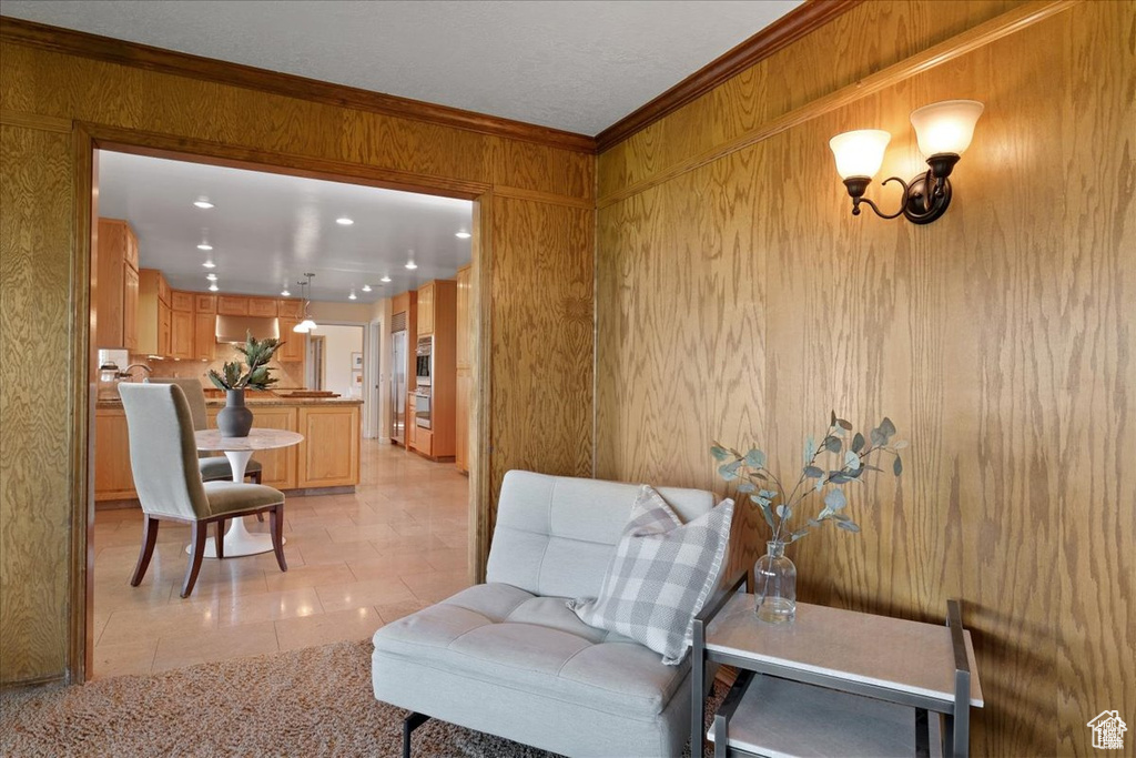 Living area featuring wooden walls, light tile patterned flooring, and ornamental molding