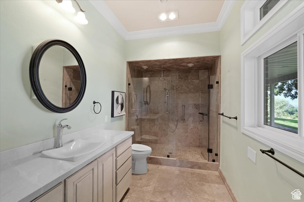 Bathroom with ornamental molding, vanity, a shower with door, tile patterned flooring, and toilet