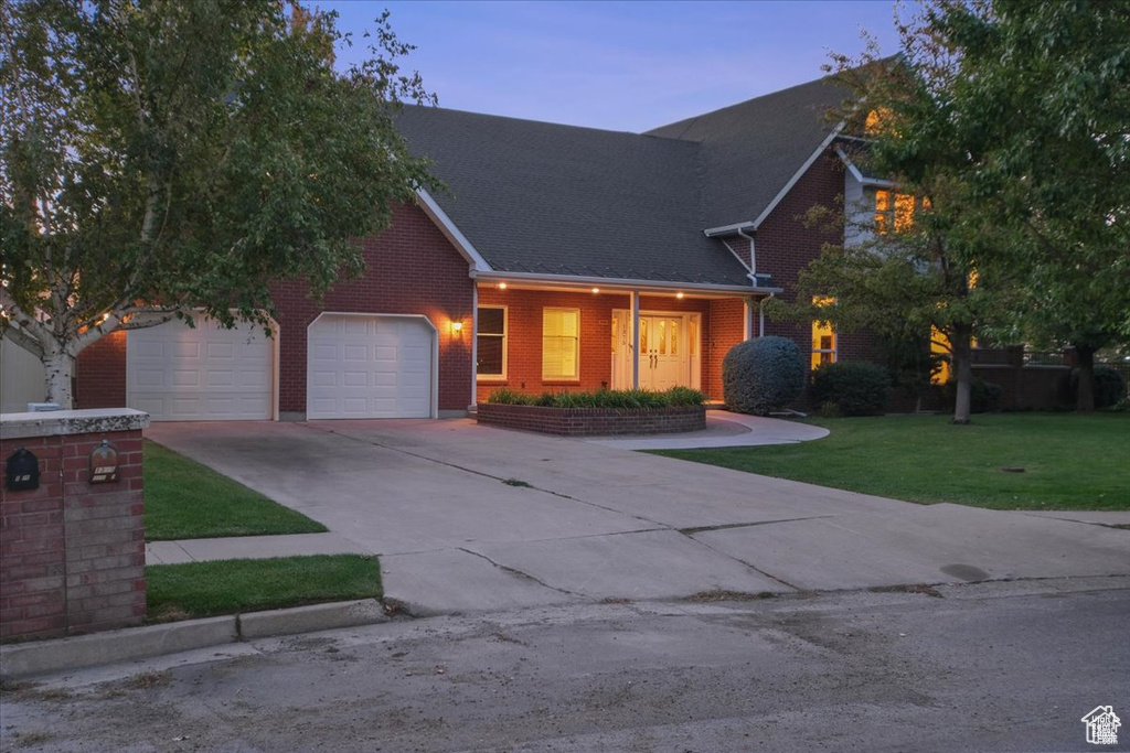 View of front of property with a garage and a yard