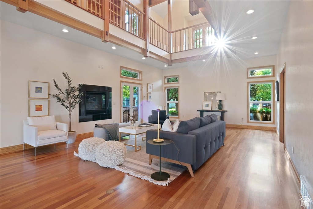 Living room with hardwood / wood-style floors, a towering ceiling, a tile fireplace, and french doors