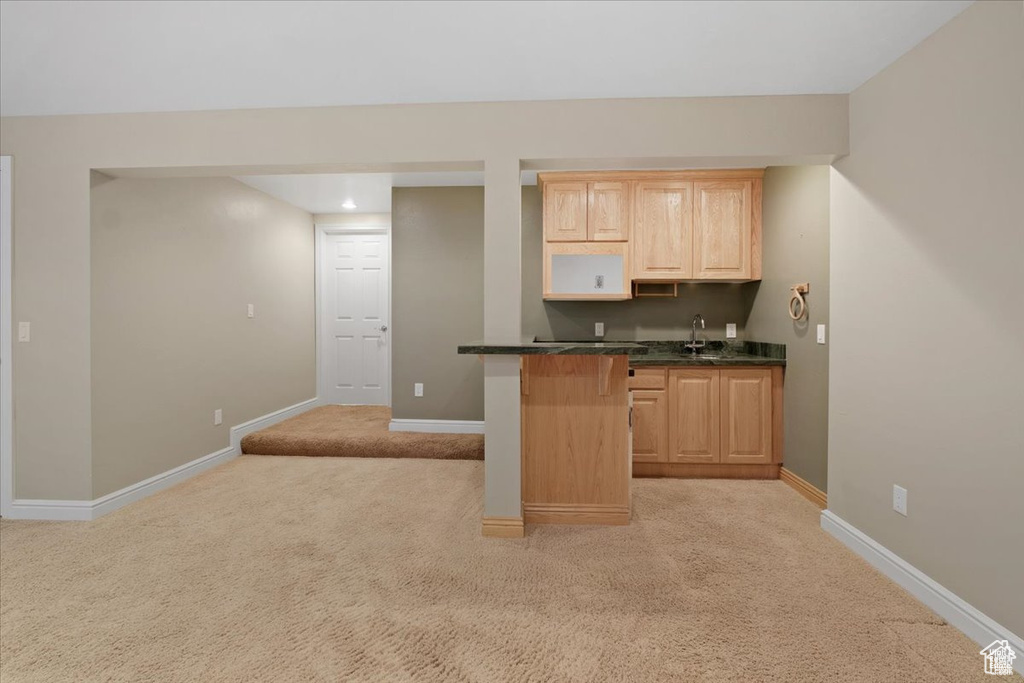 Kitchen with light carpet, light brown cabinetry, and sink
