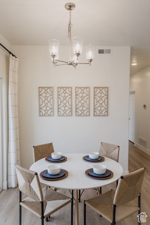 Dining area with wood-type flooring and an inviting chandelier