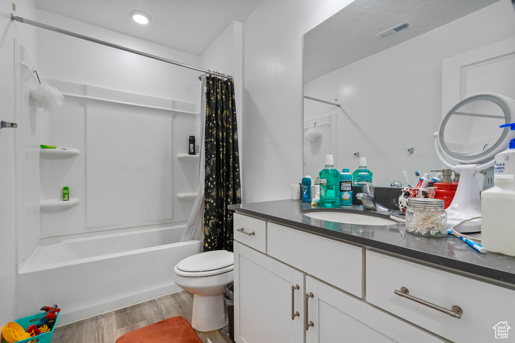 Full bathroom with toilet, shower / tub combo with curtain, vanity, and hardwood / wood-style flooring