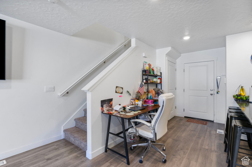 Office area with hardwood / wood-style floors and a textured ceiling