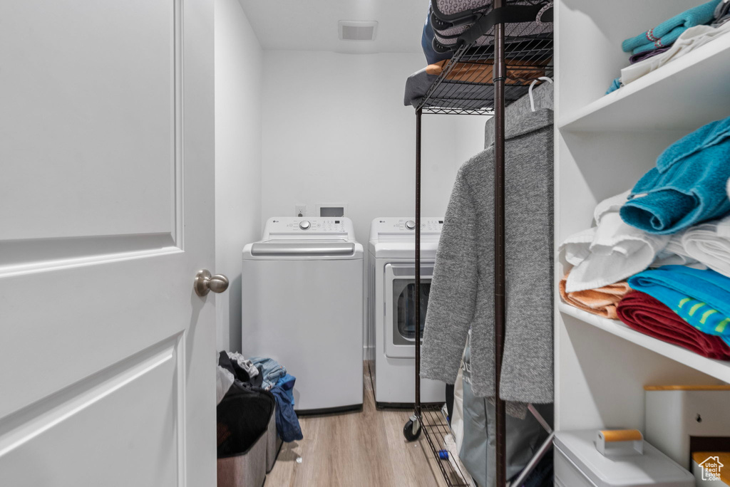 Laundry room featuring separate washer and dryer and light hardwood / wood-style flooring