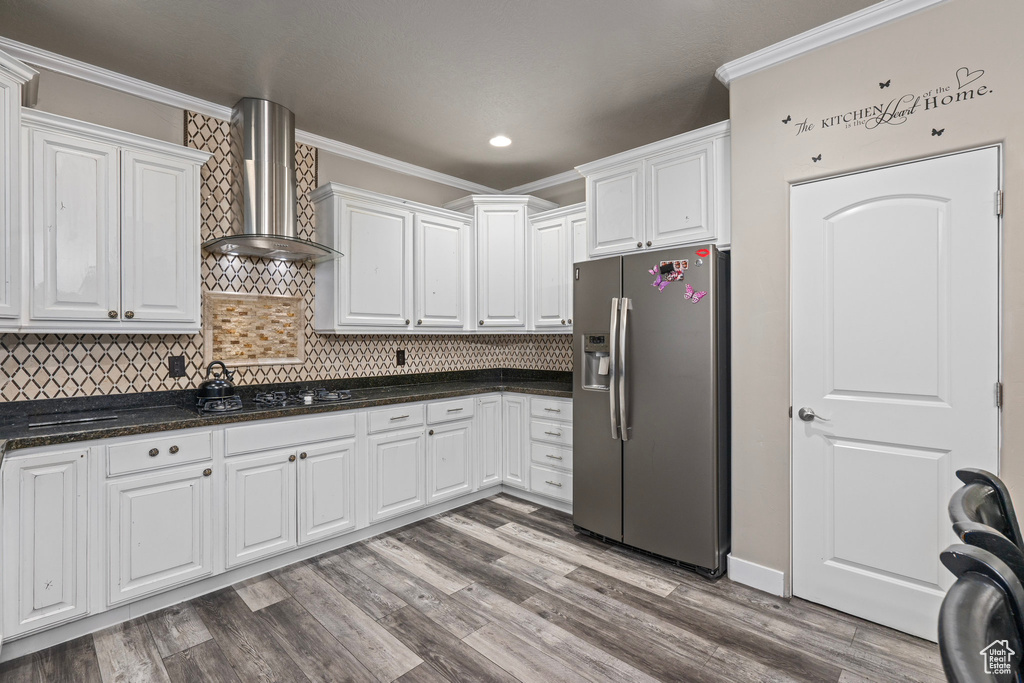 Kitchen featuring white cabinets, stainless steel fridge, light hardwood / wood-style flooring, and wall chimney range hood