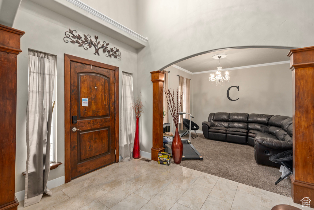 Foyer entrance with a notable chandelier, light colored carpet, and ornamental molding