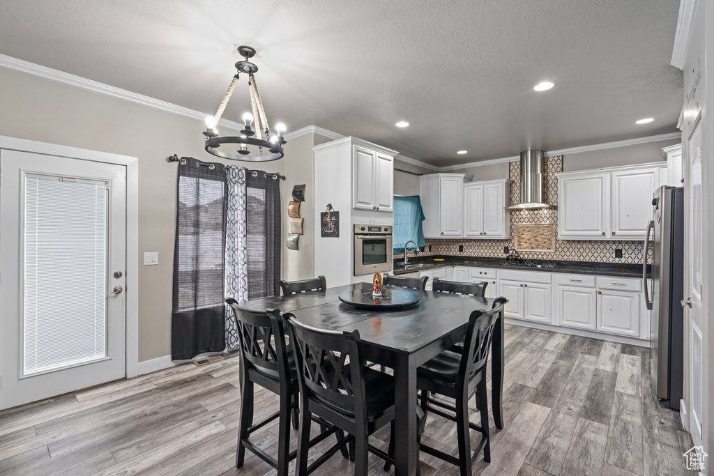 Dining area featuring sink, light wood-type flooring, ornamental molding, and an inviting chandelier