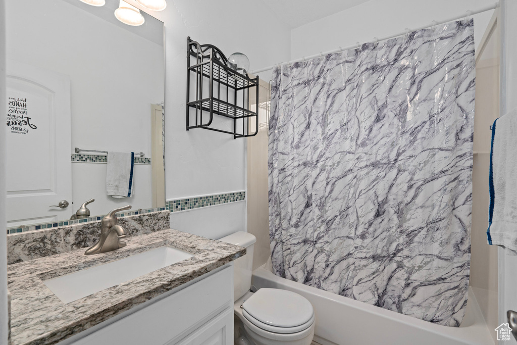 Full bathroom featuring shower / bath combo with shower curtain, vanity, and toilet