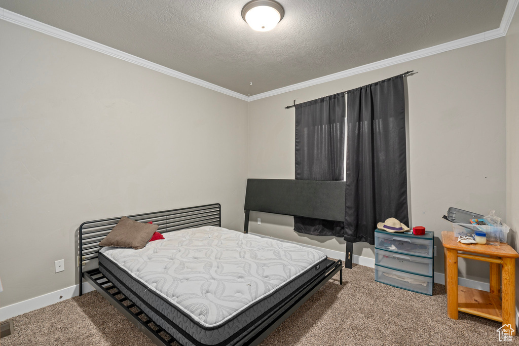 Bedroom with carpet flooring, a textured ceiling, and crown molding